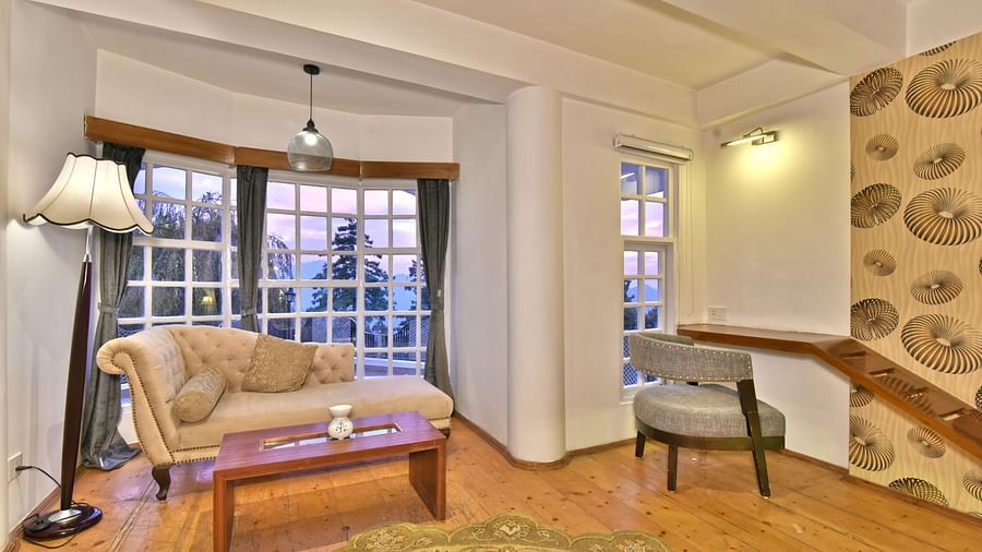 Living space of the suite featuring sofas and a chair and a fancy light hanging from the ceiling at DLS Hillcrest Resort, Shimla.